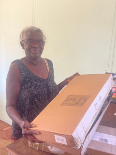 A First Nations Woman holding a box with hanging storage inside.