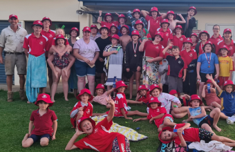 Kids from Cumnock Swimming Club dressed in red uniform with their hats.