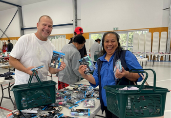 Flood-impacted community members (one male and one female, both holding baskets) pciking up donated clothing from Inala Community House