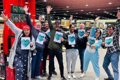 Dan's staff dressed in their PJ's, holding GIVIT heart signs in the DAN's store.